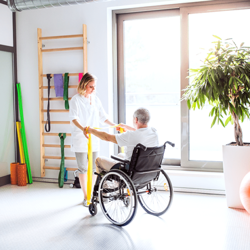 young-woman-physiotherapist-working-with-a-senior-PYSKN32